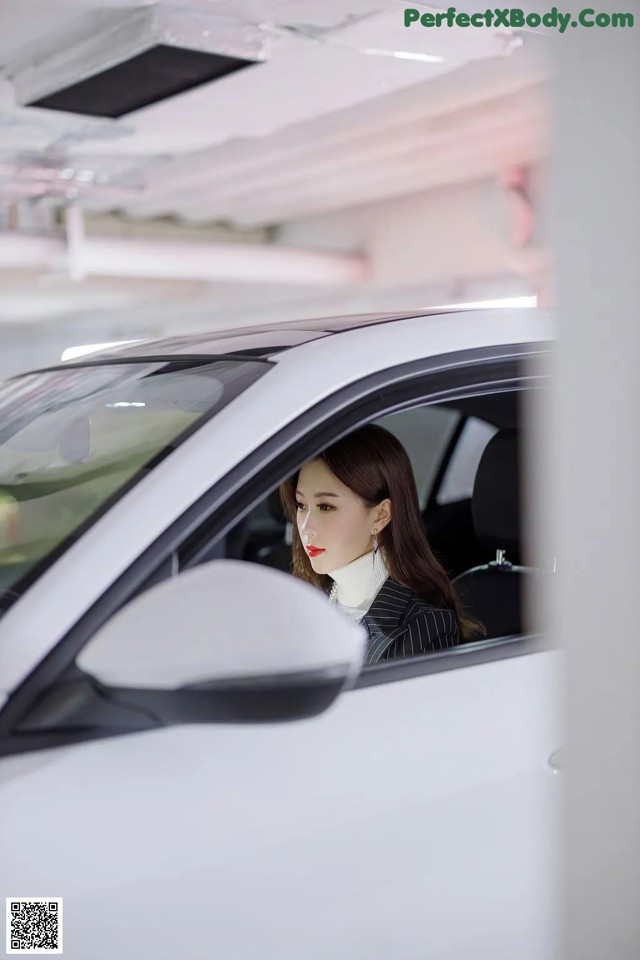 A woman sitting in the driver's seat of a white car.