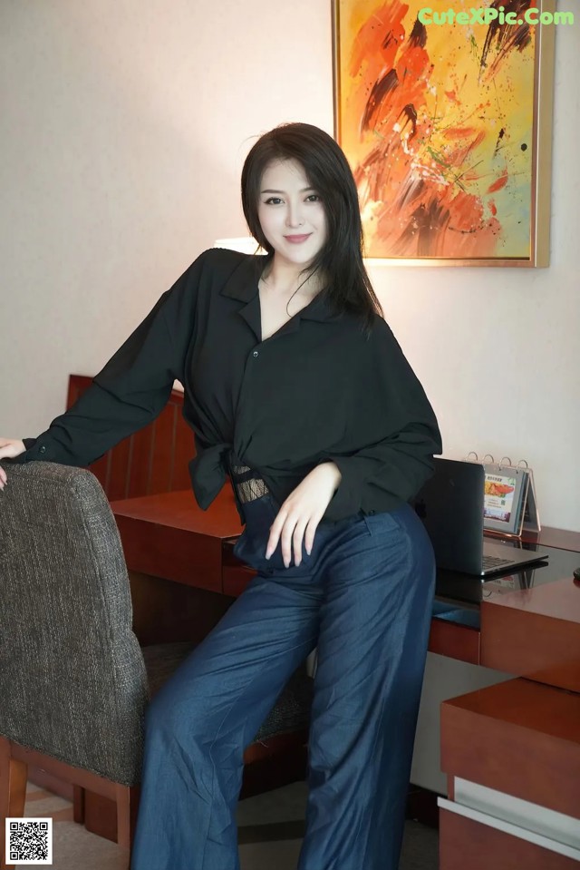 A woman sitting on a chair in front of a desk.