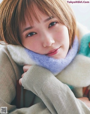 A woman in a green sweater and a pink scarf.