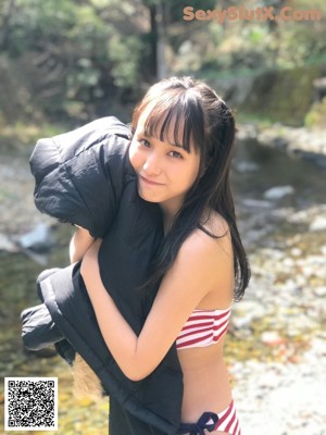 A woman in a bikini posing in front of a river.