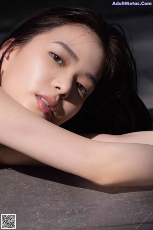 A woman laying on a table with her hand on her head.