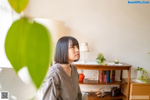 A woman crouching on the floor in front of a bookshelf.