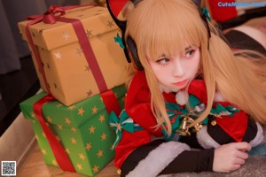 A woman in a cat costume sitting on the floor next to a Christmas tree.