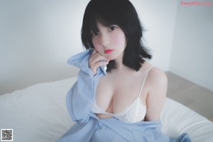 A woman sitting on top of a bed next to a television.