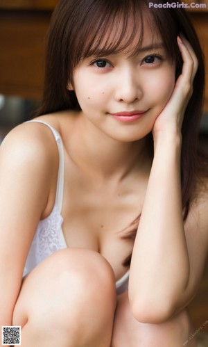 A woman in a blue bra top looking out a window.