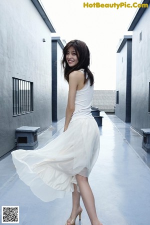 A woman leaning against a window in a white room.
