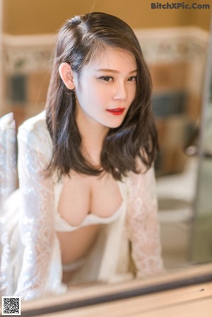 A woman in a white dress sitting on a bathtub.