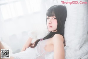 A woman laying on top of a bed covered in white fur.