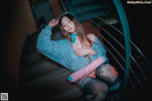 A woman in a blue shirt and camouflage leggings is sitting on some stairs.