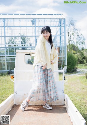 A woman sitting on the ground wearing a colorful sweater.