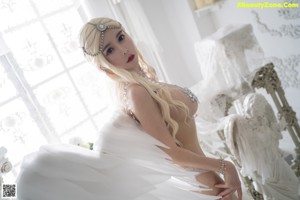A woman in a white lingerie sitting on a bed.