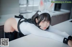 A woman in a bunny costume posing on a couch.