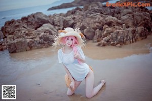 A woman in a white shirt and a cat hat on a beach.