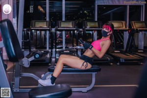 A woman wearing a pink sports bra top and black shorts.