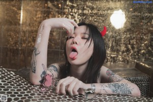 A woman with horns and tattoos sitting on a couch.