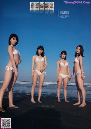 A group of young women standing next to each other on a beach.