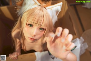 A naked woman in a box with a cat ears on her head.