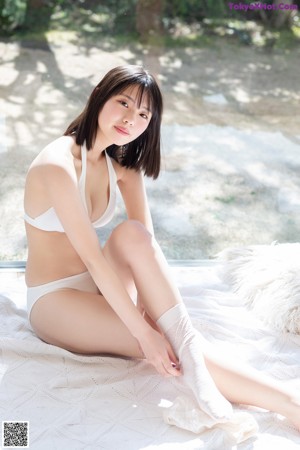 A woman in a white bikini laying on a bed.