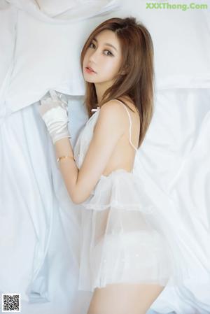 A woman laying on a bed in a white lingerie.