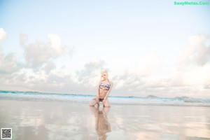 A woman in a bikini sitting in the water.