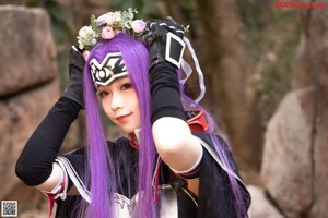 A woman with purple hair holding a bouquet of flowers.