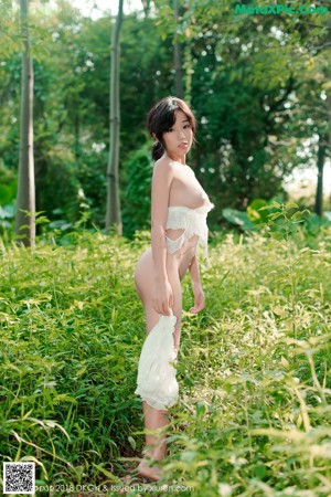 A woman in a white dress is standing in the grass.