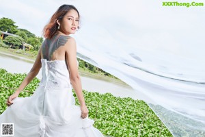 A woman in a white dress posing on a wooden bridge.