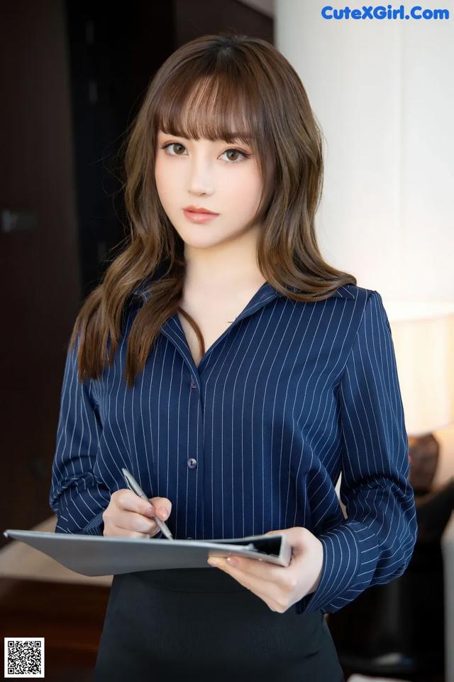 A woman in a blue shirt and black skirt holding a tablet.
