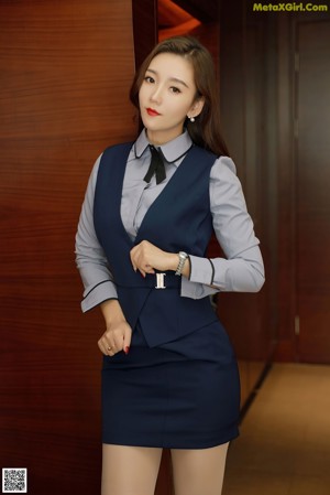 A woman in a blue shirt and black skirt posing for a picture.