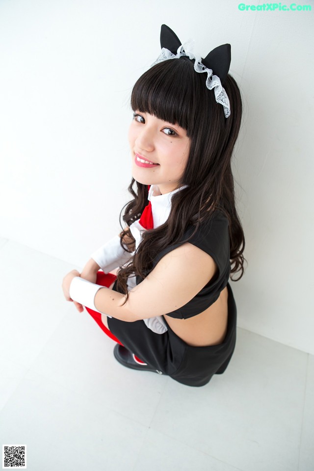 A woman in a black and white outfit sitting on the floor.