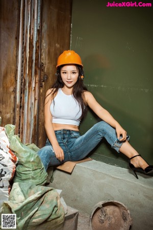 A woman wearing a hard hat standing in front of a building.