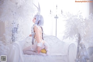 A woman in a white bunny costume posing in front of a mirror.