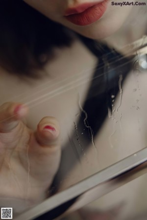 A woman in a black lingerie is looking through a glass window.