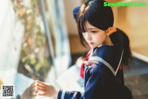 A woman in a sailor outfit sitting on a bench.