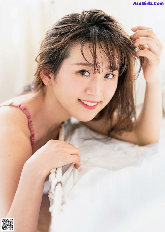 A woman laying on top of a bed next to a pillow.