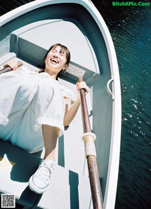 A naked woman standing in a bathtub holding a white towel.