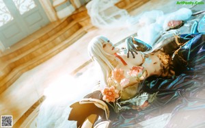 A woman with long white hair sitting on a bed with flowers.