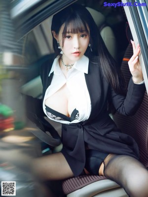 A woman in black stockings and a white shirt is sitting in a car.